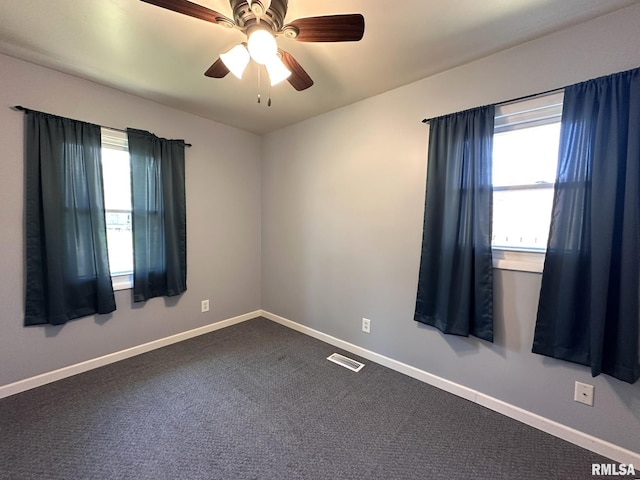 spare room with visible vents, baseboards, ceiling fan, and dark colored carpet