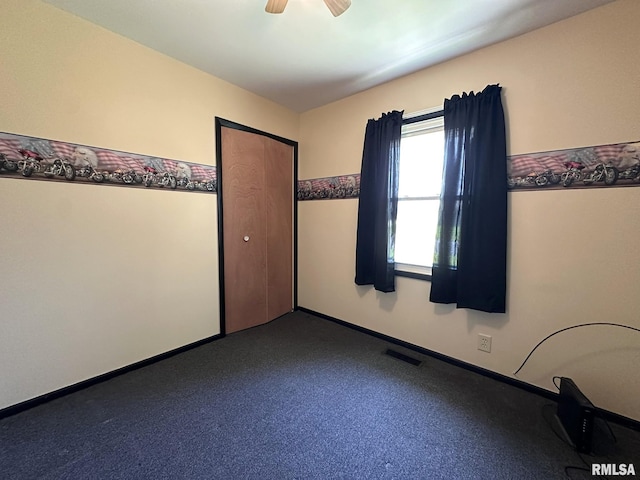 empty room featuring a ceiling fan, baseboards, visible vents, and dark carpet