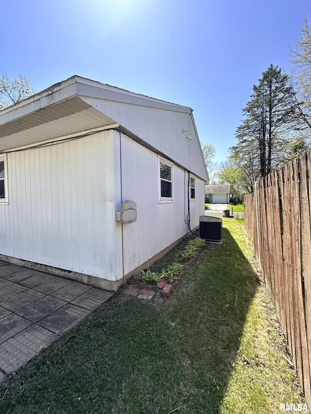view of home's exterior with fence, central air condition unit, and a lawn
