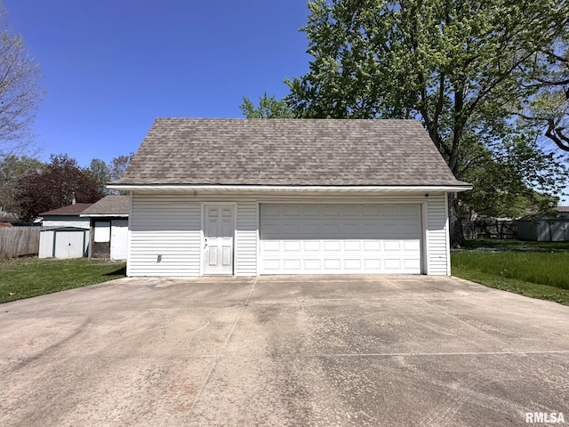detached garage featuring fence and a shed