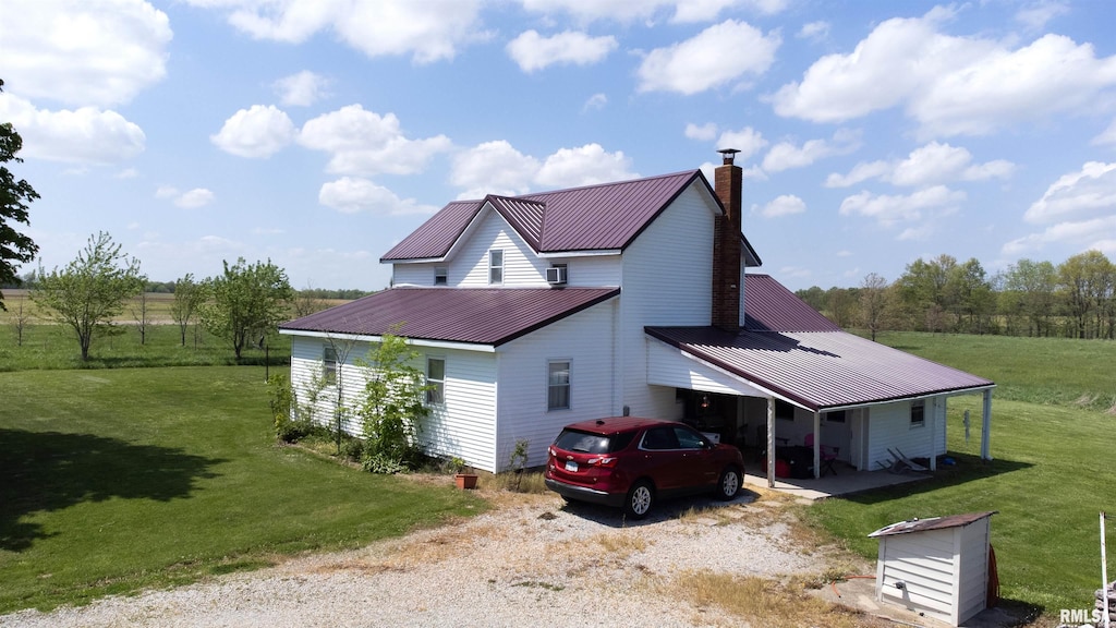 view of side of property featuring a chimney, dirt driveway, a yard, and metal roof