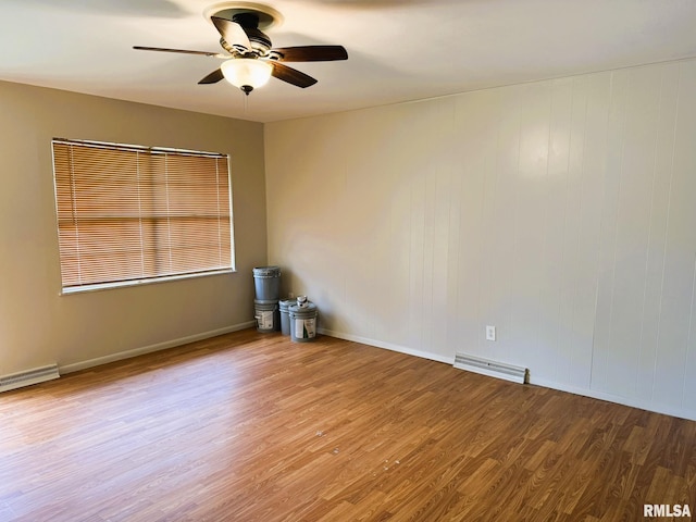 empty room featuring visible vents, wood finished floors, baseboards, ceiling fan, and baseboard heating