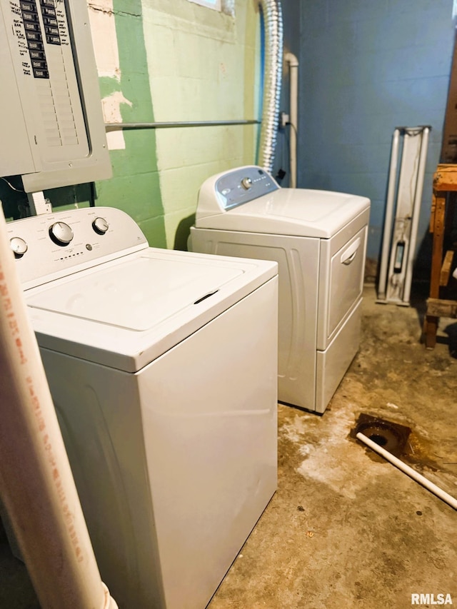 laundry room featuring concrete block wall, laundry area, independent washer and dryer, and electric panel