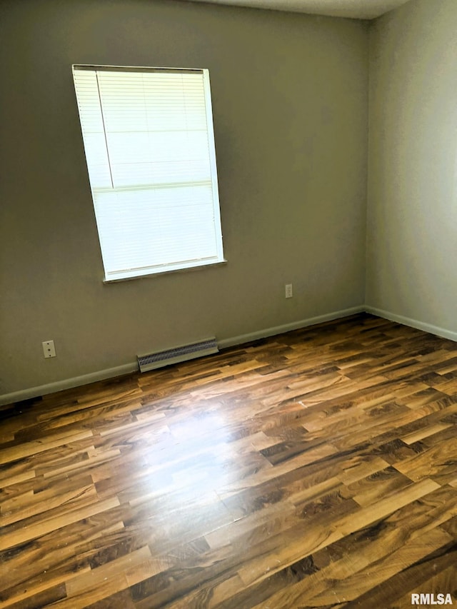 empty room with baseboards, visible vents, and dark wood-type flooring