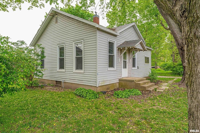 view of side of home featuring a yard and a chimney