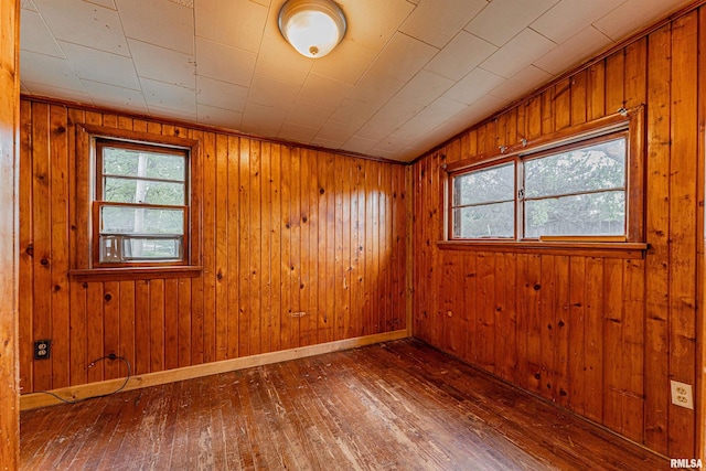 empty room featuring wooden walls, baseboards, and hardwood / wood-style flooring