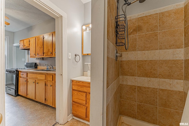 bathroom featuring a textured ceiling, a tile shower, tile patterned floors, and vanity