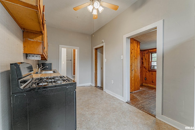 kitchen featuring baseboards, a ceiling fan, and black gas range