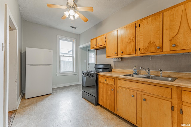 kitchen with visible vents, freestanding refrigerator, black range with gas stovetop, light countertops, and a sink