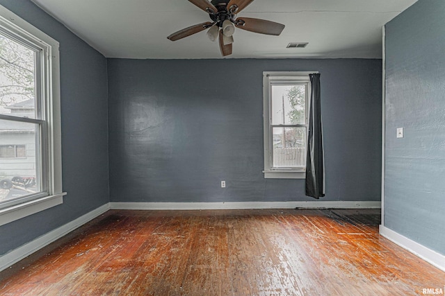 spare room with baseboards, a ceiling fan, hardwood / wood-style floors, and visible vents