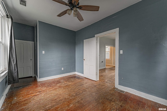 empty room with visible vents, baseboards, ceiling fan, and wood finished floors