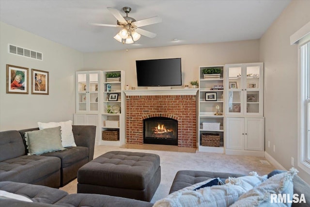 living room featuring visible vents, ceiling fan, a fireplace, and light colored carpet