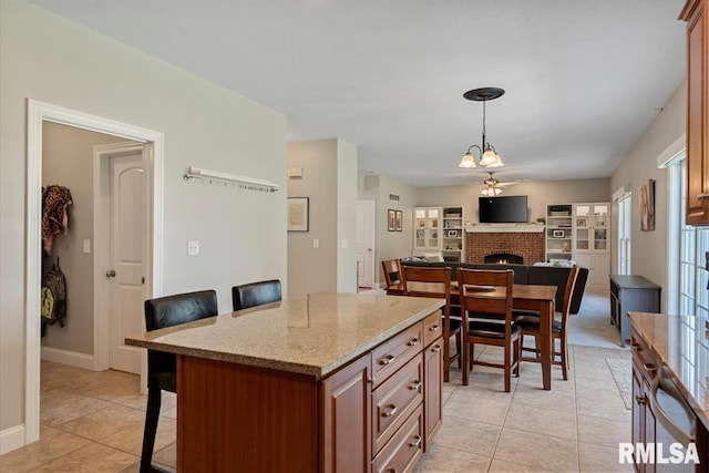 kitchen featuring pendant lighting, a brick fireplace, open floor plan, a kitchen bar, and light tile patterned floors