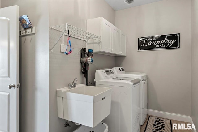 washroom with a sink, separate washer and dryer, baseboards, and cabinet space