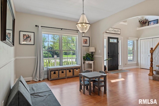 interior space with a healthy amount of sunlight, arched walkways, an inviting chandelier, and light wood-style flooring