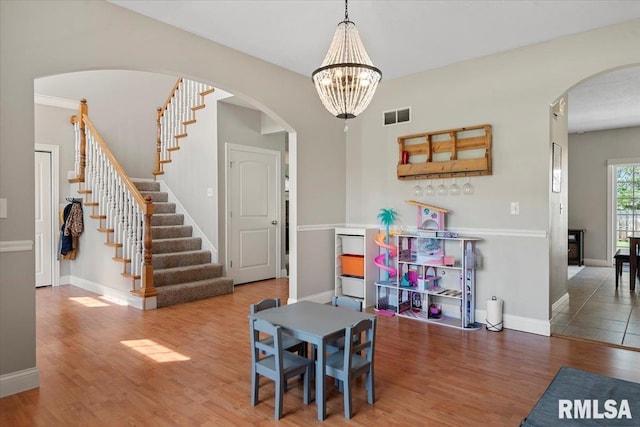 dining space featuring visible vents, baseboards, wood finished floors, and stairway
