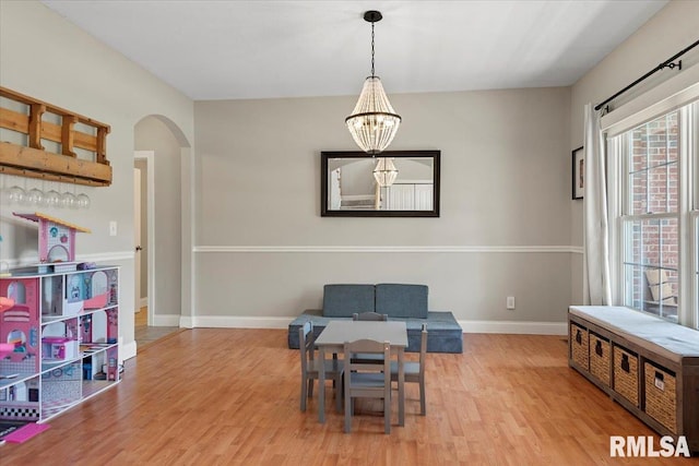 living area with arched walkways, baseboards, an inviting chandelier, and wood finished floors