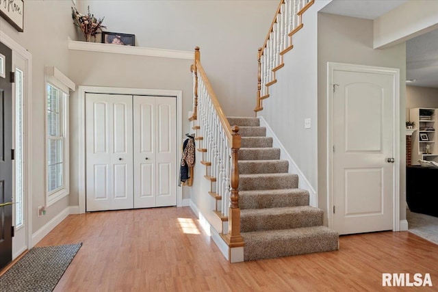 entryway featuring light wood-style floors, baseboards, and stairway