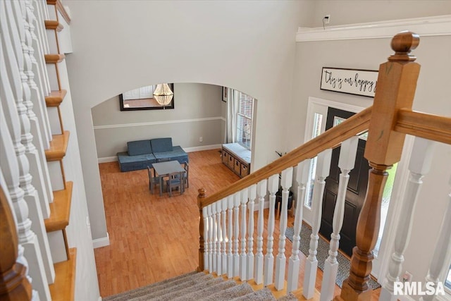 stairway with arched walkways, baseboards, and wood finished floors