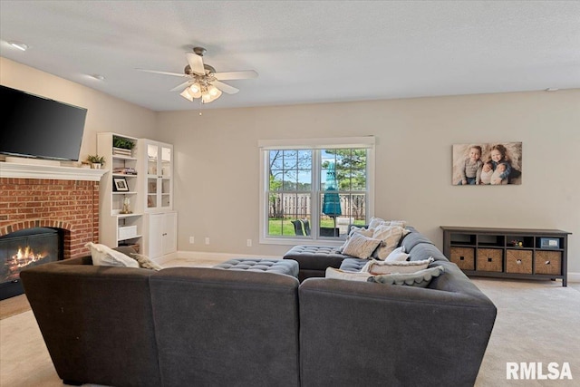 living area featuring a ceiling fan, baseboards, light colored carpet, and a fireplace