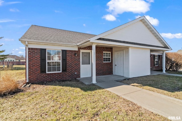 ranch-style home featuring brick siding, a shingled roof, and a front yard