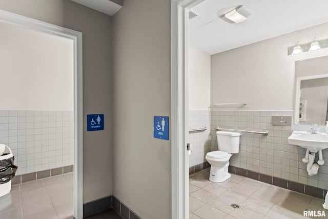half bathroom with wainscoting, tile walls, toilet, and tile patterned floors
