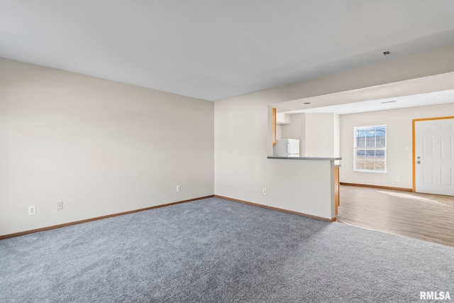 unfurnished living room featuring baseboards and carpet