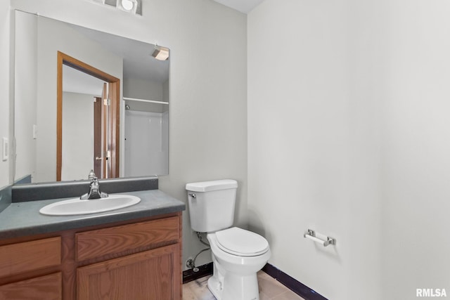 bathroom featuring toilet, baseboards, and vanity