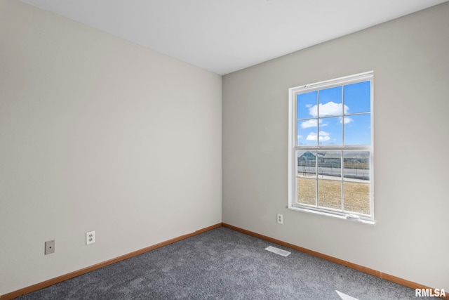 empty room featuring baseboards, visible vents, and dark colored carpet