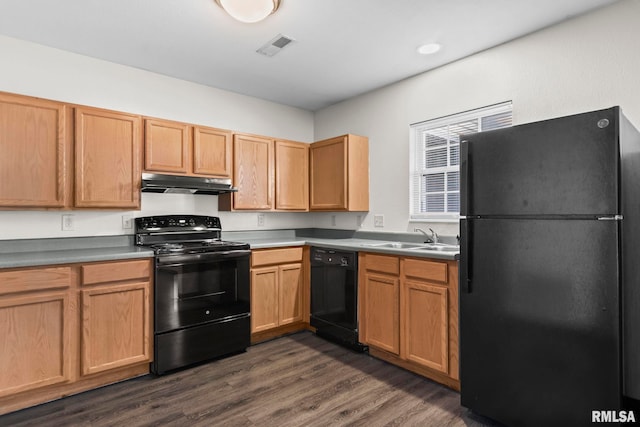 kitchen with a sink, dark wood finished floors, under cabinet range hood, visible vents, and black appliances