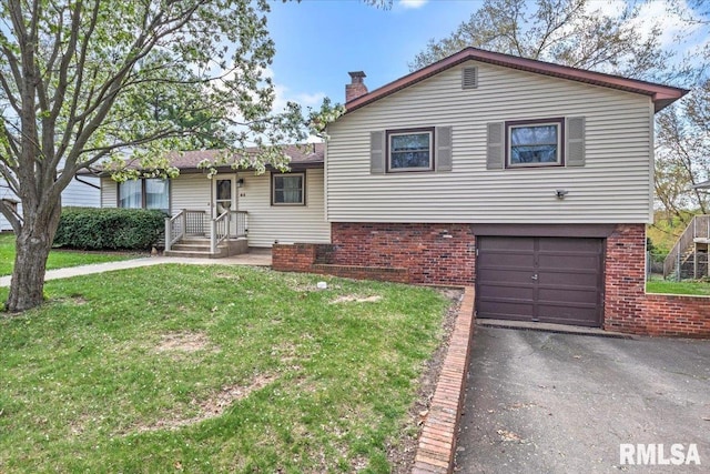 tri-level home featuring an attached garage, aphalt driveway, brick siding, a front yard, and a chimney