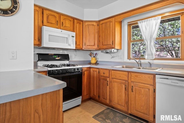 kitchen featuring a sink, brown cabinets, white appliances, and light countertops