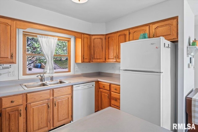 kitchen featuring white appliances, brown cabinetry, a sink, and light countertops