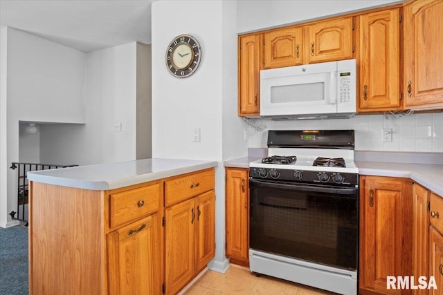 kitchen with a peninsula, white microwave, light countertops, backsplash, and gas stove