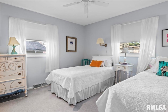 carpeted bedroom with a ceiling fan, baseboards, visible vents, and multiple windows