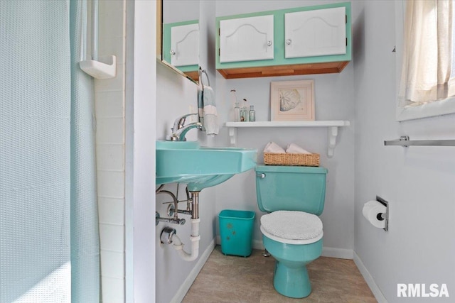 bathroom featuring baseboards, a shower with shower curtain, and toilet