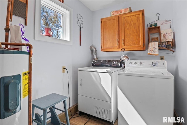 clothes washing area featuring cabinet space, independent washer and dryer, water heater, and light wood-style floors