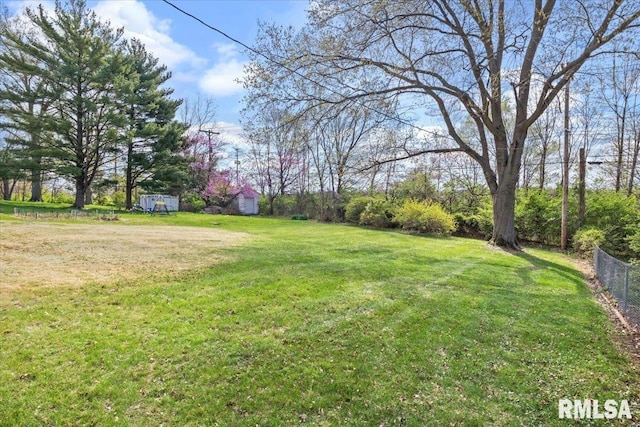 view of yard with an outdoor structure, fence, and a shed