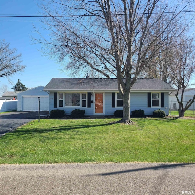 ranch-style home featuring a detached garage, fence, and a front lawn
