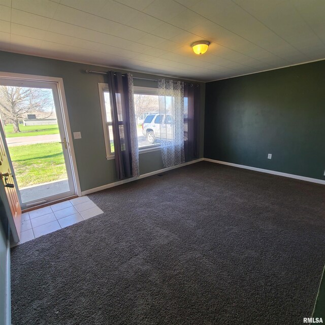 carpeted empty room featuring baseboards, plenty of natural light, and tile patterned floors