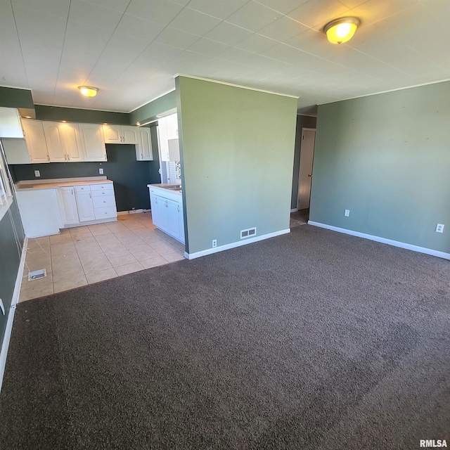 kitchen featuring light carpet, white cabinetry, baseboards, open floor plan, and visible vents