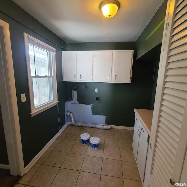 laundry area featuring baseboards, cabinet space, light tile patterned floors, and washer hookup