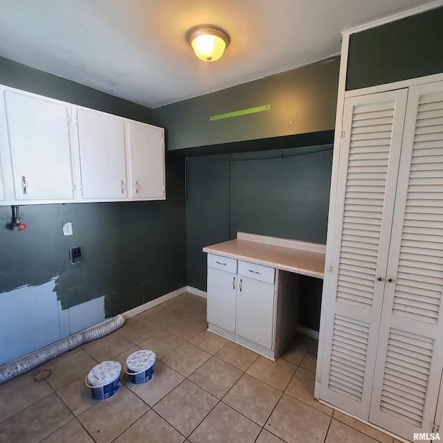 laundry area featuring baseboards, cabinet space, and light tile patterned floors