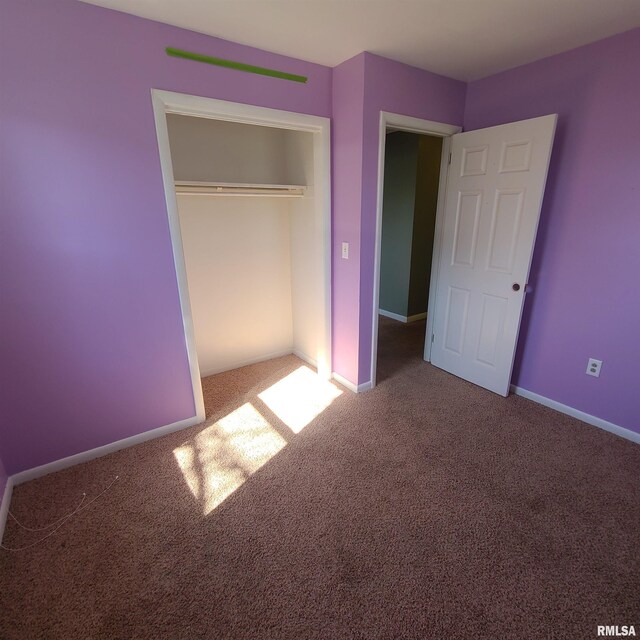 unfurnished bedroom featuring baseboards, carpet, and a closet