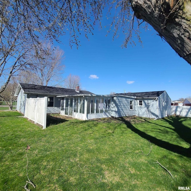 back of property featuring a lawn, a chimney, and a sunroom