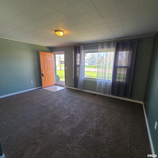spare room with baseboards, visible vents, and dark carpet