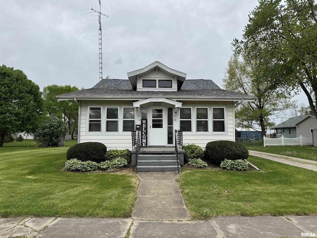 bungalow with a shingled roof and a front yard