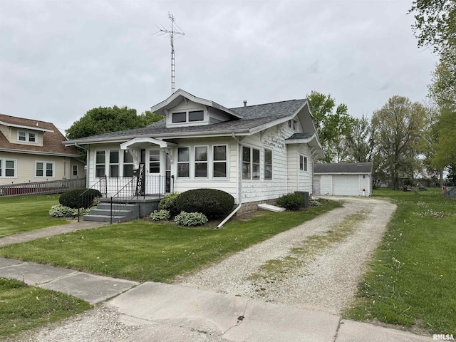 bungalow-style house with roof with shingles, dirt driveway, a front lawn, and a garage