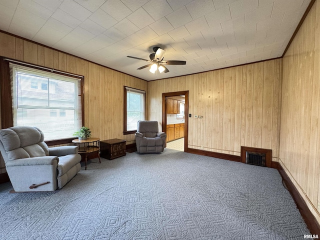 living area with visible vents, ceiling fan, wood walls, and carpet