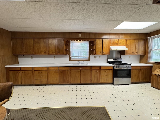kitchen with open shelves, under cabinet range hood, brown cabinets, and gas range